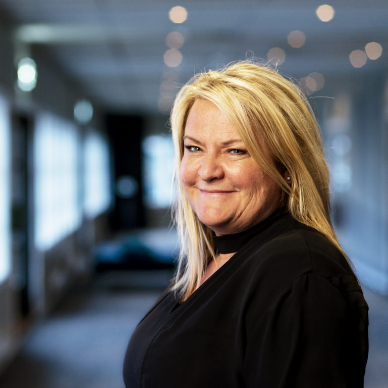 May Helen Hetland Ervik, smilende med uklar bakgrunn. Portrett. Foto.