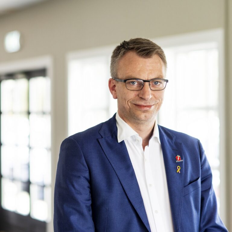 Terje Settenøy smilende foran uklar bakgrunn. portrett. Foto