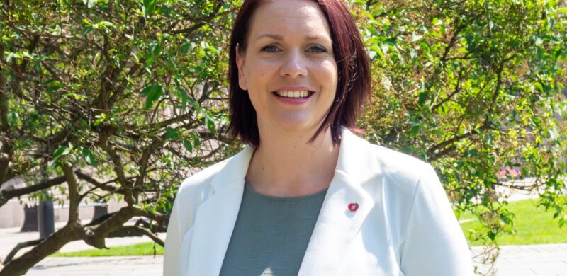 Åshild Bruun-Gundersen smilende med grønne trær i bakgrunnen. Portrett. Foto