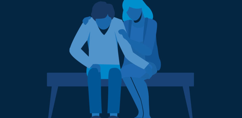 Kvinne som sitter trøstende ved siden av en mann som virker nedbrutt. Alt i blåtoner. Illustrasjon