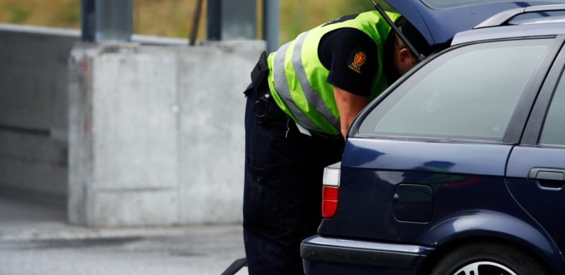 Toller som inspiserer en mørk bil. Foto.