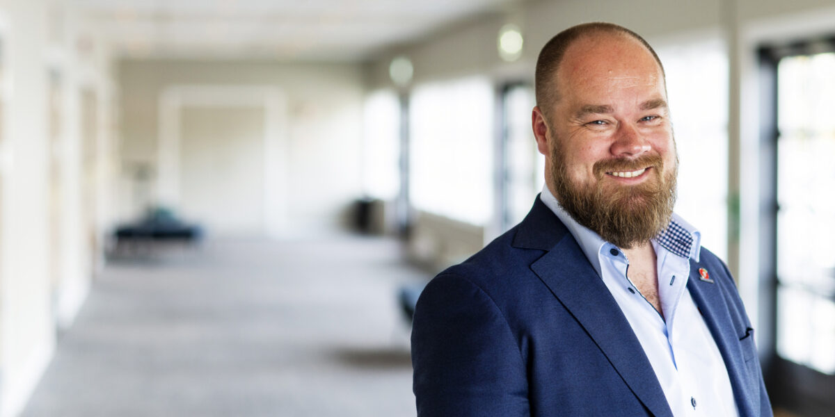 Truls Gihlemoen smilende foran uskarp bakgrunn. Foto.